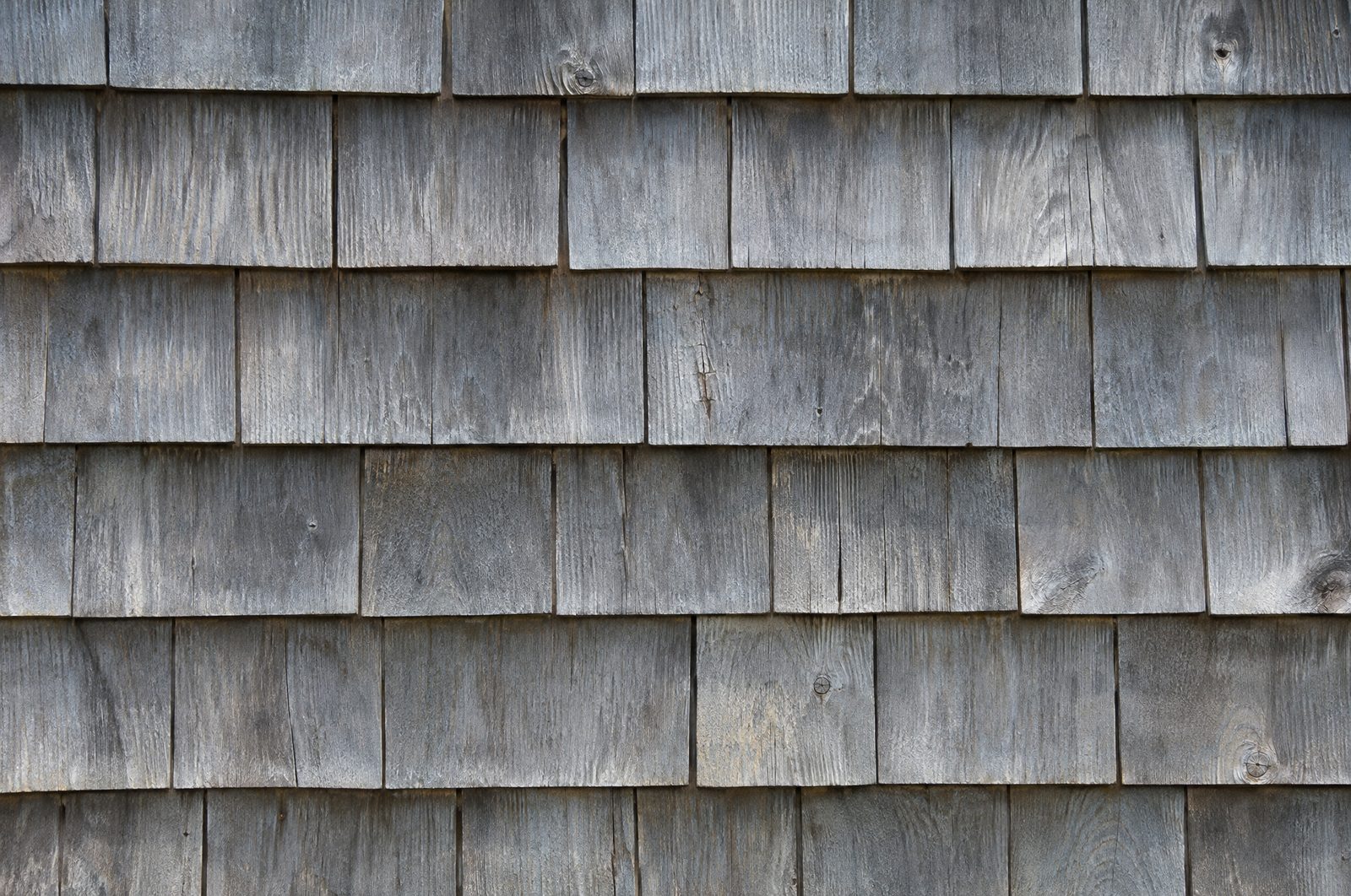 Close-up of weathered silver-gray cedar shingle siding
