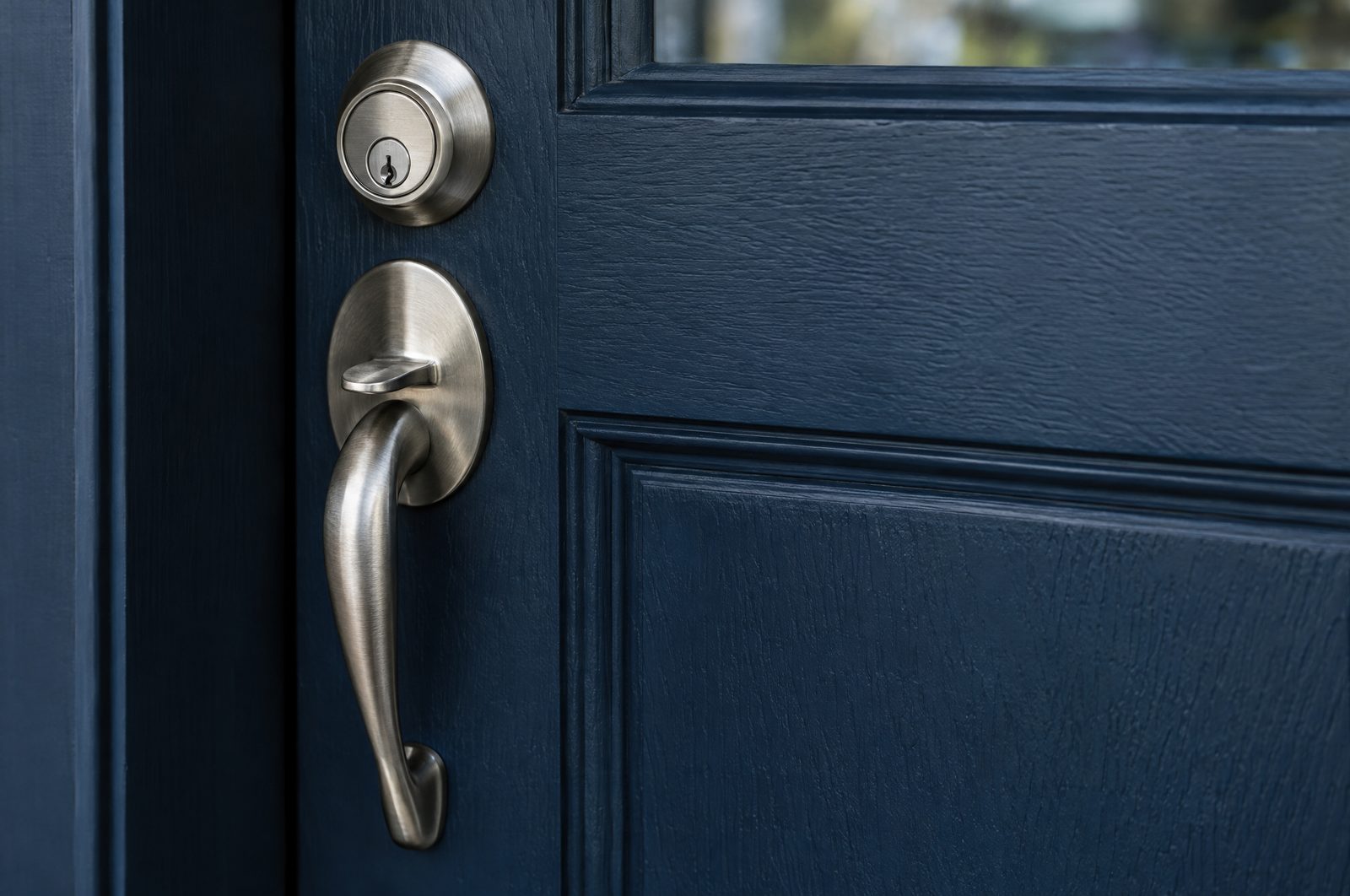 Brushed stainless handleset and deadbolt on a navy entry door