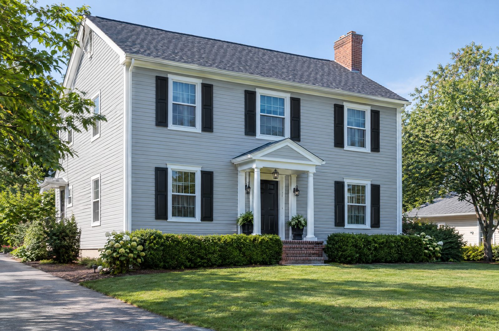 Colonial home with light gray vinyl clapboard siding, white trim, and black shutters